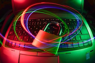 A padlock sits on a laptop keyboard with glowing red, green, and blue light trails swirling around, creating a sense of security and cyber awareness.