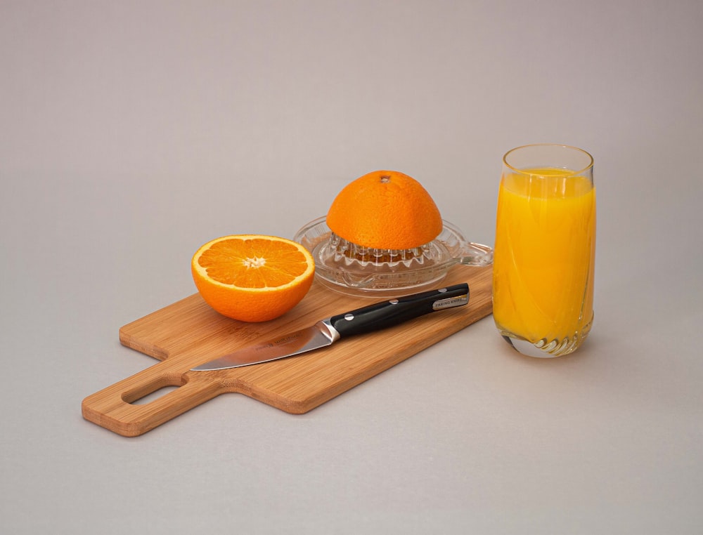 clear drinking glass with yellow liquid on brown wooden chopping board