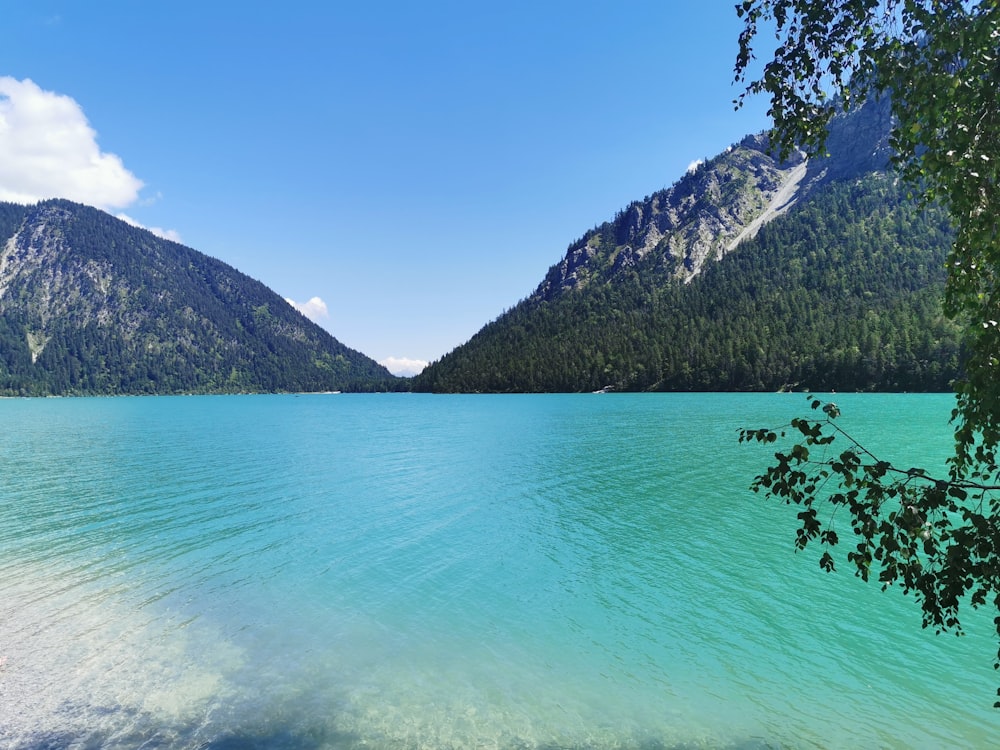 green lake near mountain under blue sky during daytime