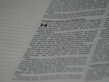 Close-up of worn sacred Buddhist texts carefully preserved on a wooden shelf bathed in soft light.