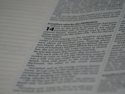 A close-up photo of a person reading an old Hindi manuscript under natural sunlight, highlighting the texture of the paper.