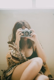 woman in black and white floral bikini top holding black and silver dslr camera