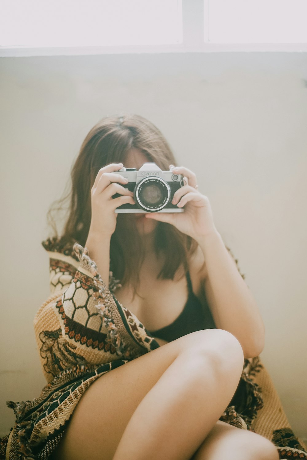 woman in black and white floral bikini top holding black and silver dslr camera