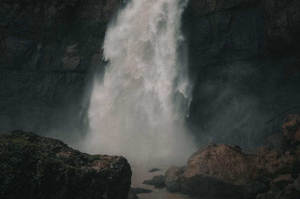 water falls on rocky shore during daytime