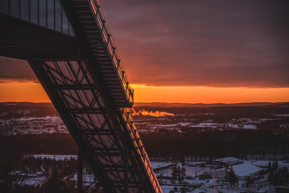 brown wooden bridge over body of water during sunset