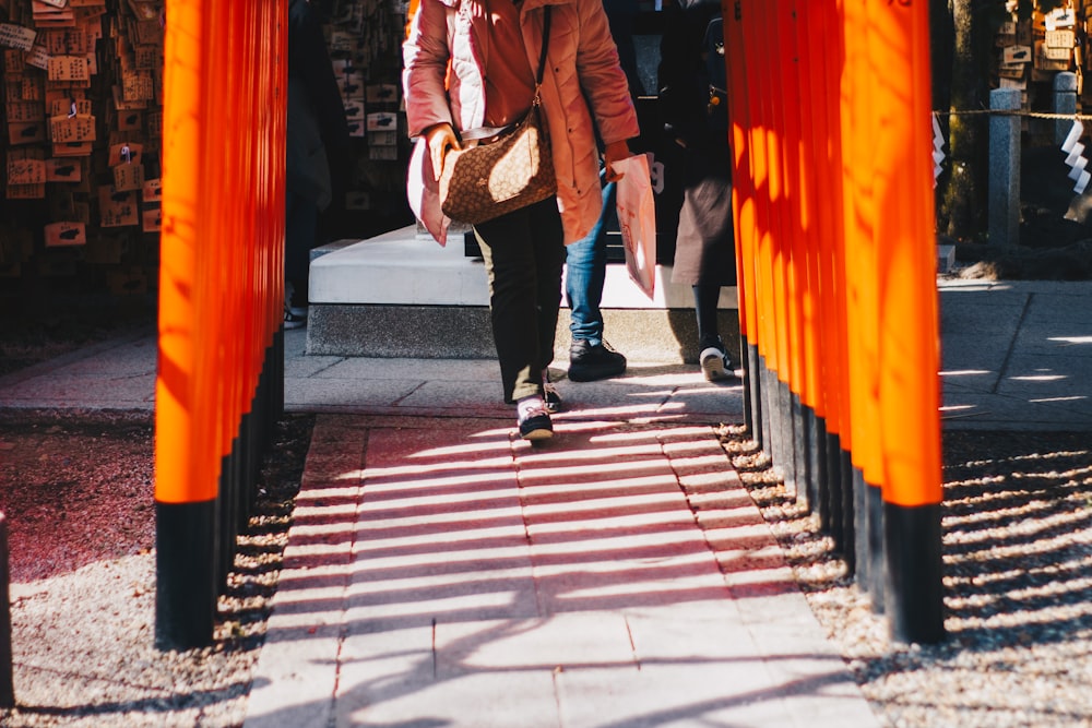 woman in brown coat walking on sidewalk during daytime