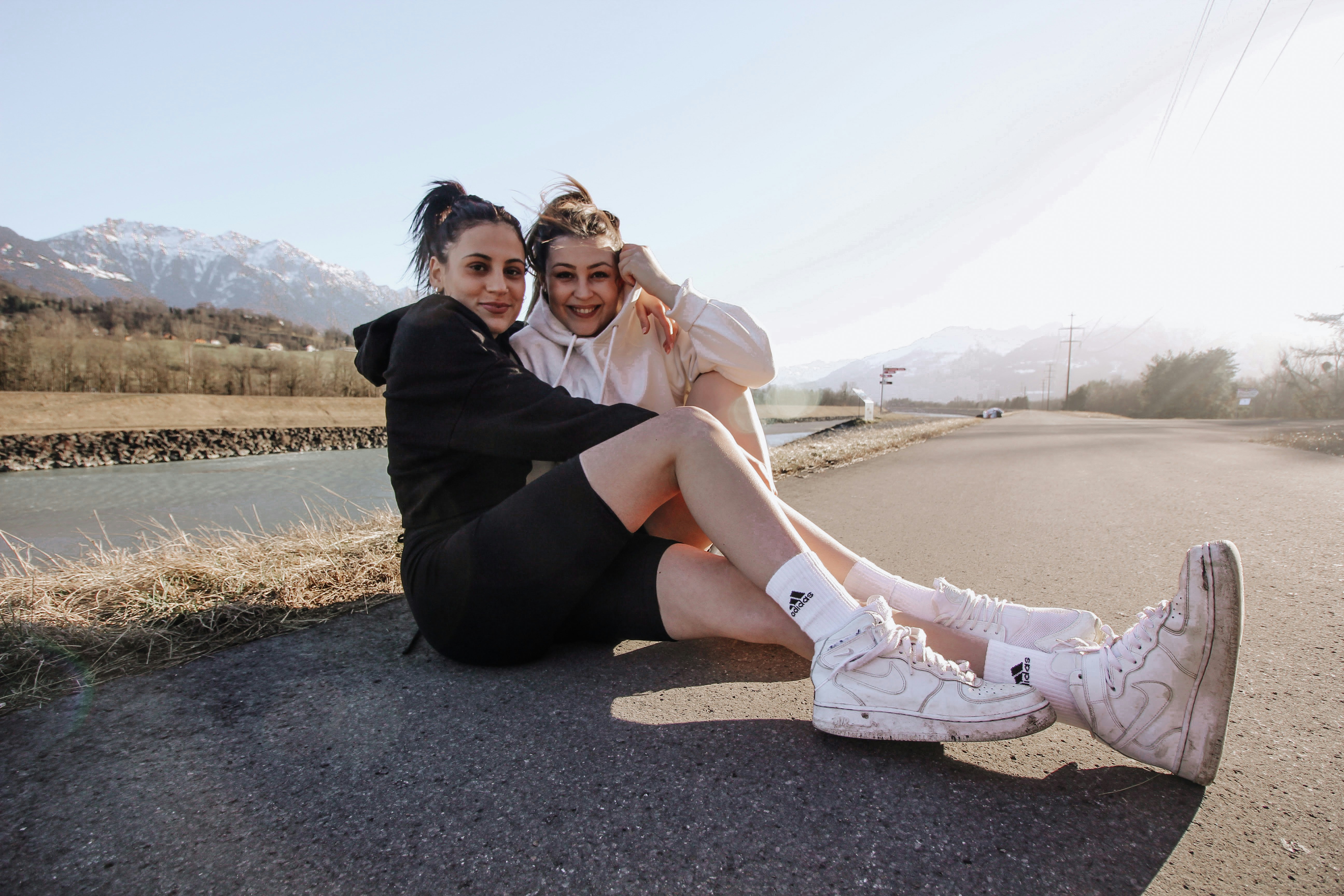 2 women sitting on gray concrete road during daytime