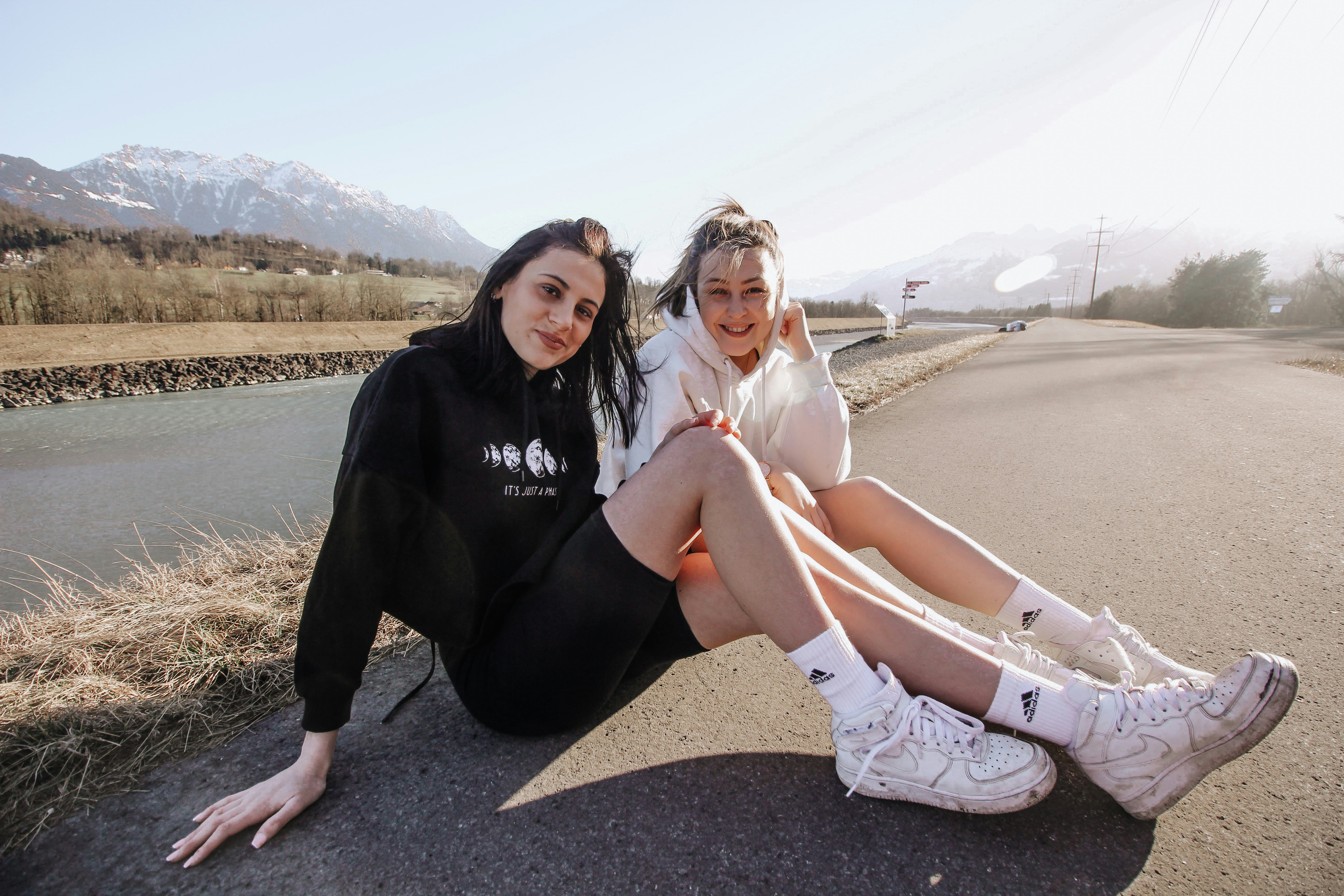 2 women sitting on gray sand during daytime
