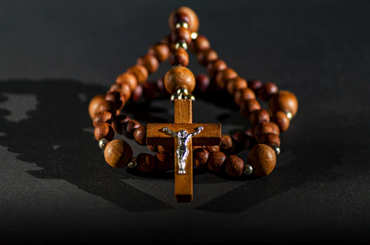 A serene close-up of a wooden rosary resting gently on an open Bible with soft candlelight in the background.