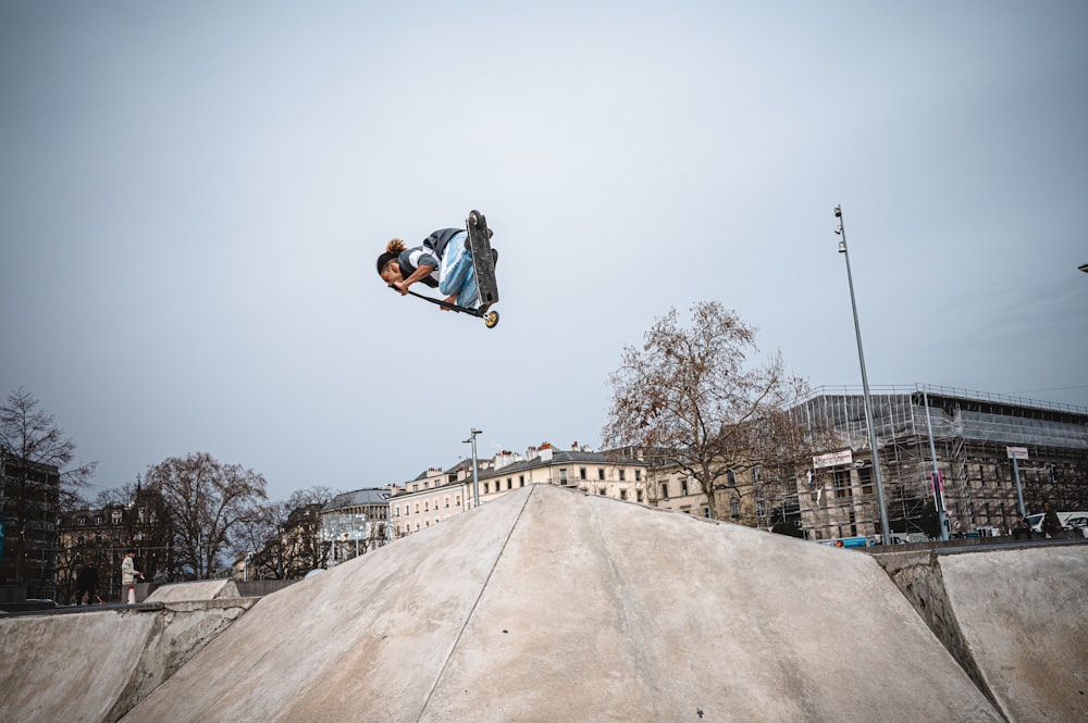 man in blue jacket and black pants doing skateboard stunts on gray concrete floor during daytime