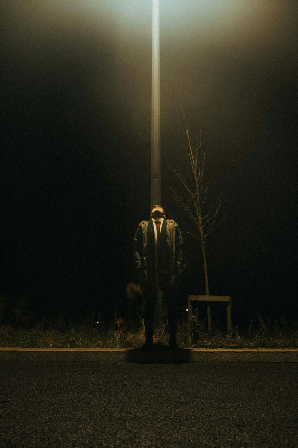 man standing near white light post during night time