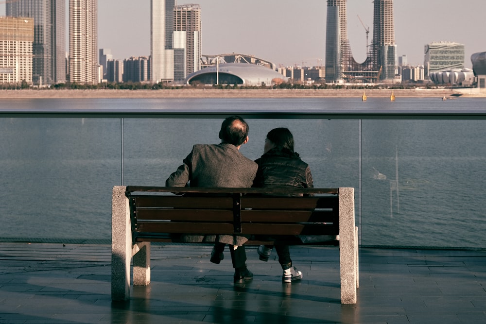 man and woman sitting on brown wooden bench