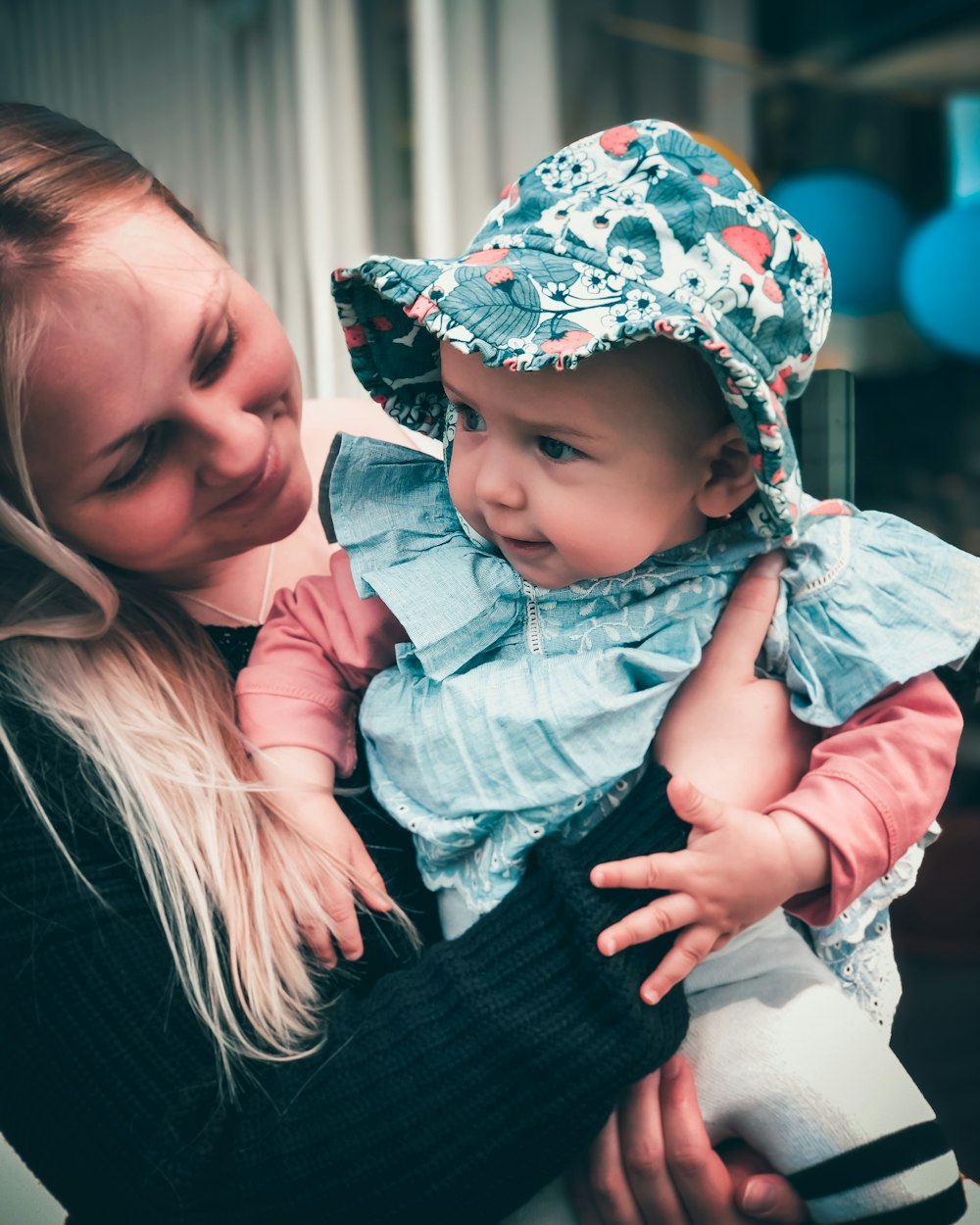 donna in camicia nera a maniche lunghe che trasporta il bambino in giacca di jeans blu