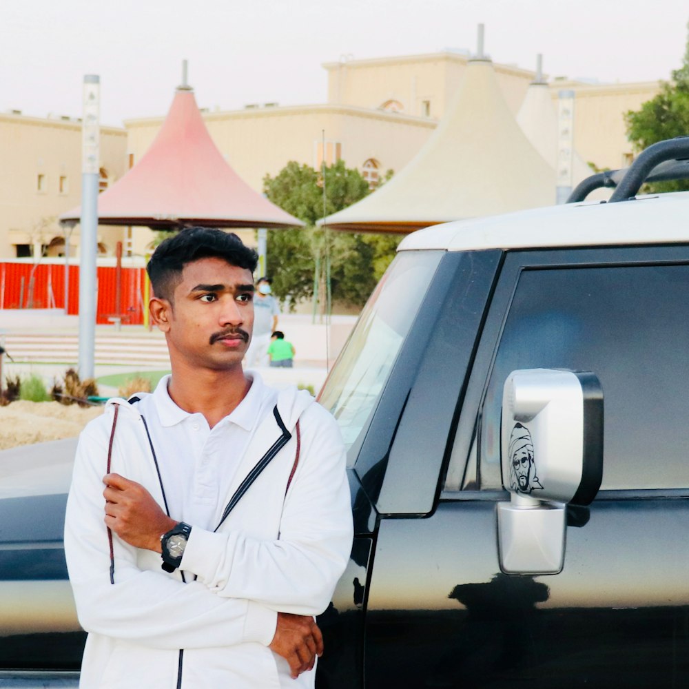 man in white dress shirt standing beside silver car during daytime