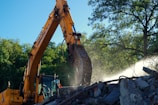 yellow excavator near green trees during daytime
