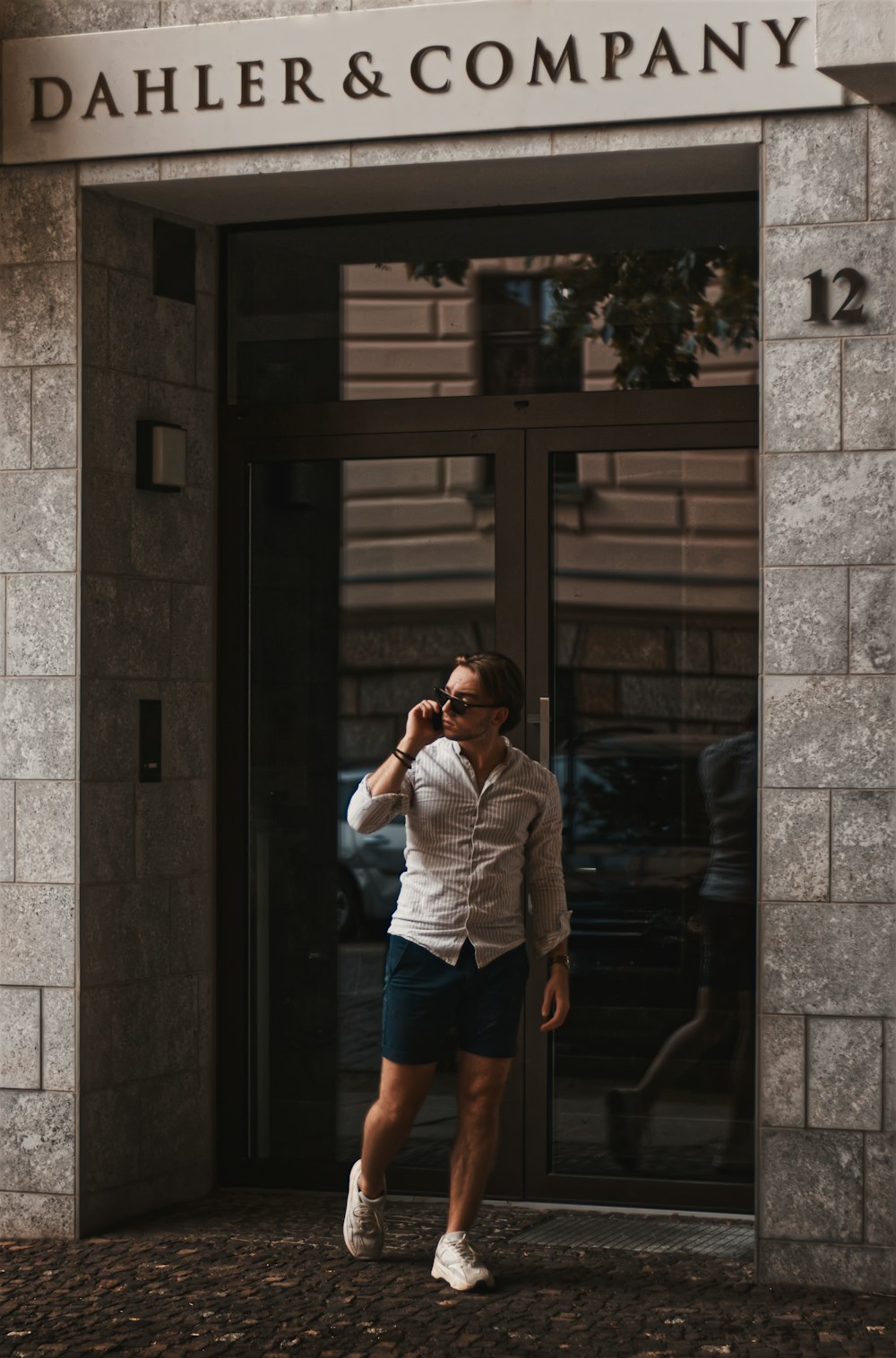 woman in white long sleeve shirt and blue denim shorts standing beside brown wooden door