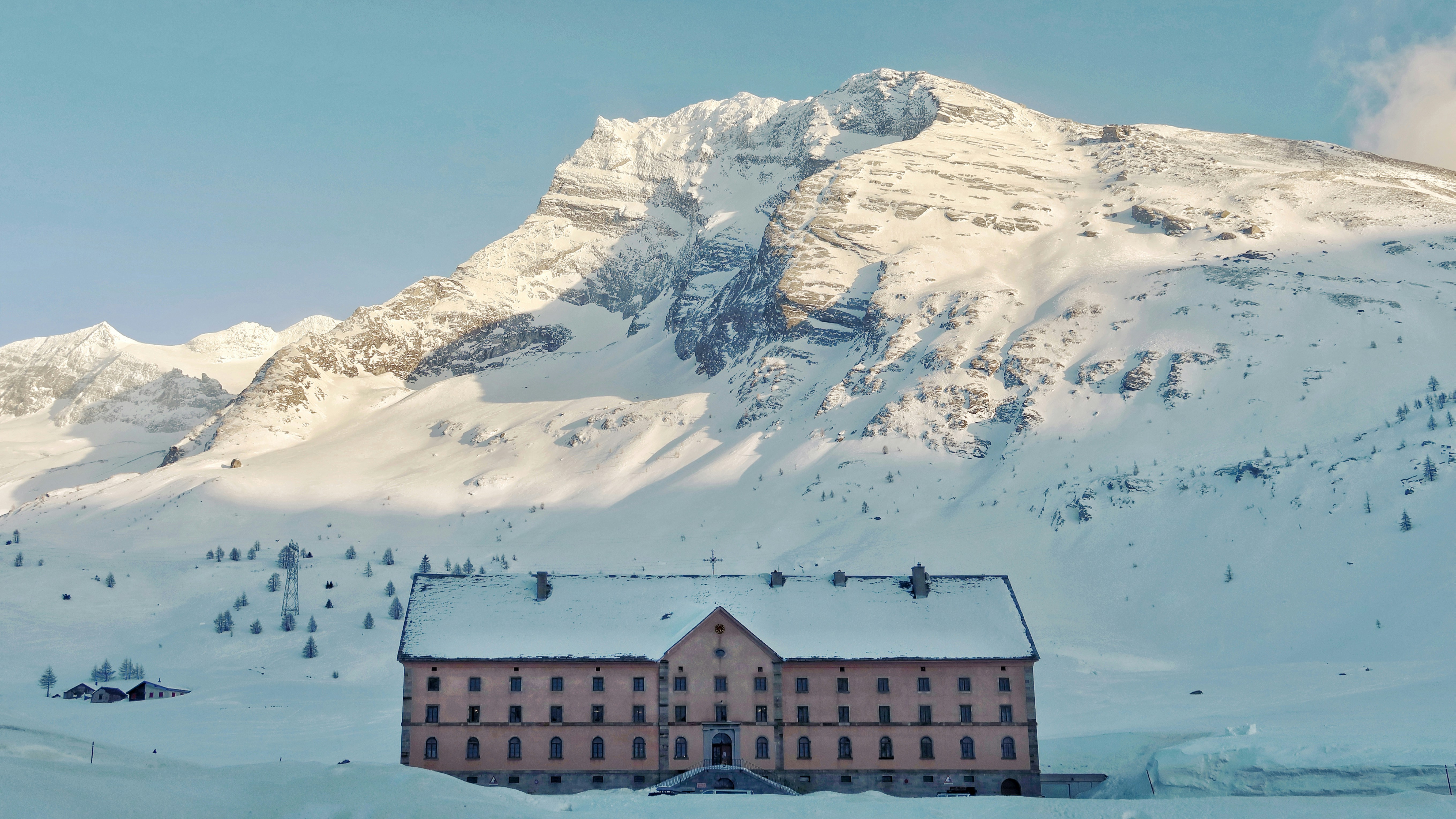 brown and white house near snow covered mountain during daytime