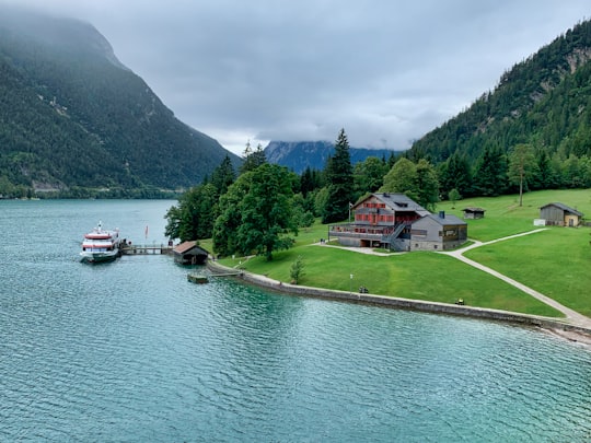 white and red house near lake and green trees during daytime in Achenkirch Austria