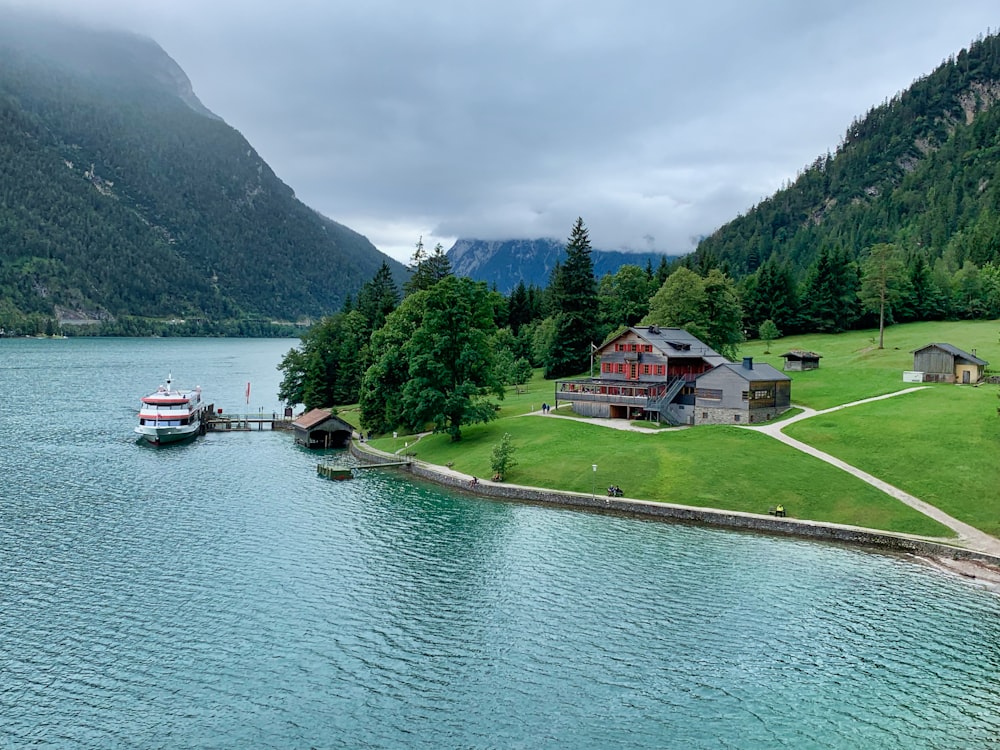 Casa blanca y roja cerca del lago y árboles verdes durante el día