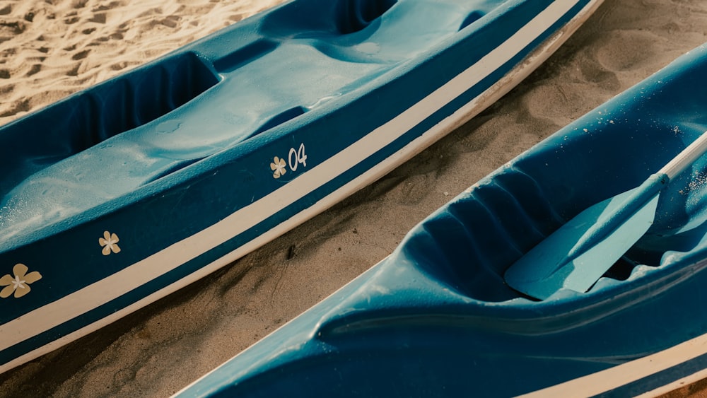 blue and white kayak on white sand during daytime