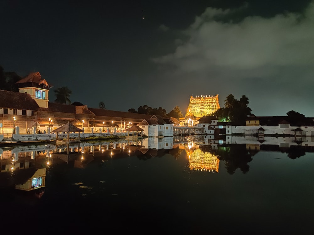 Bâtiment en béton blanc et brun près d’un plan d’eau pendant la nuit