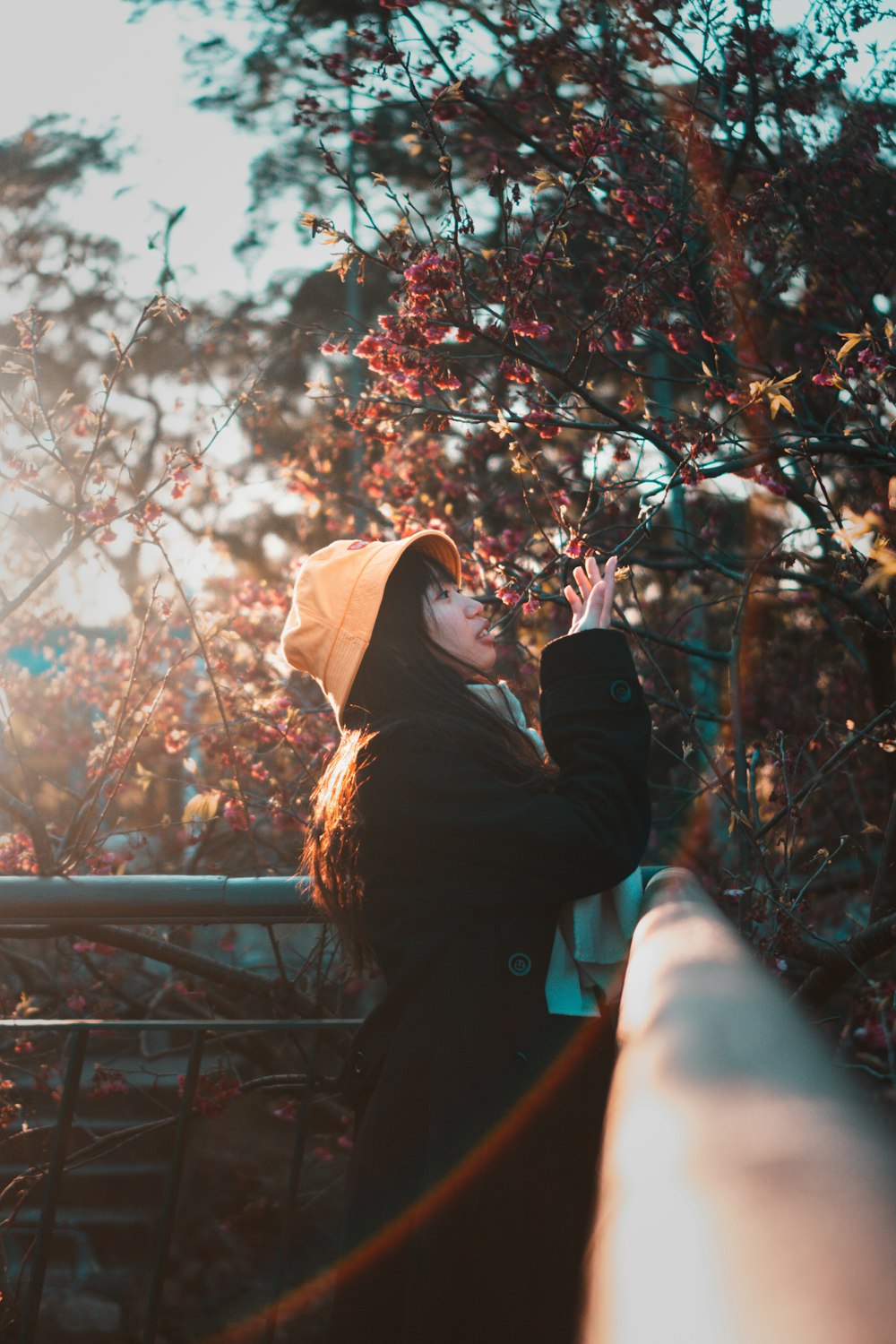 woman in black jacket and brown knit cap standing near brown leaf tree during daytime