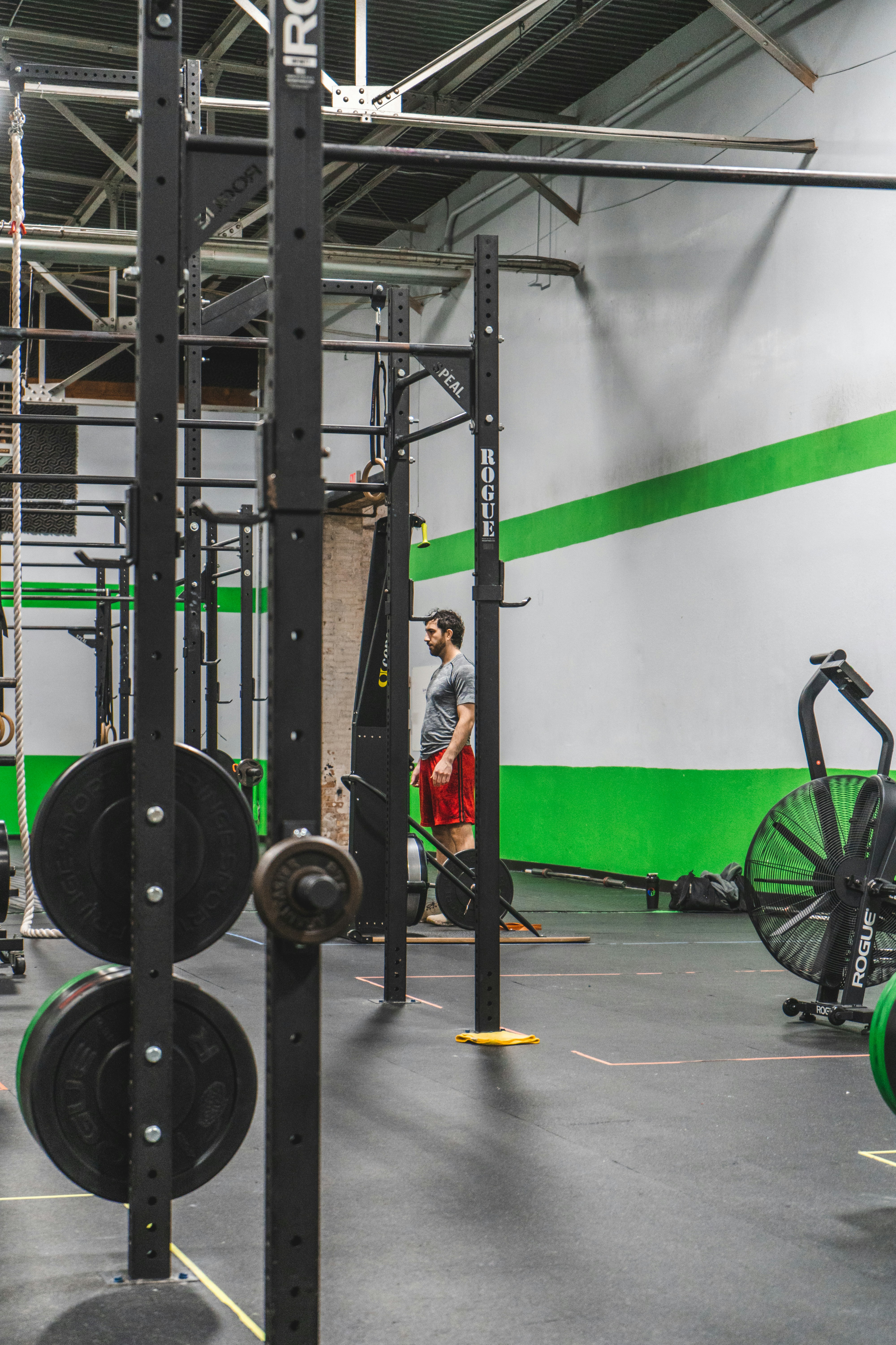 Muscular athlete chalking hands in a dark, gritty warehouse gym with heavy chains