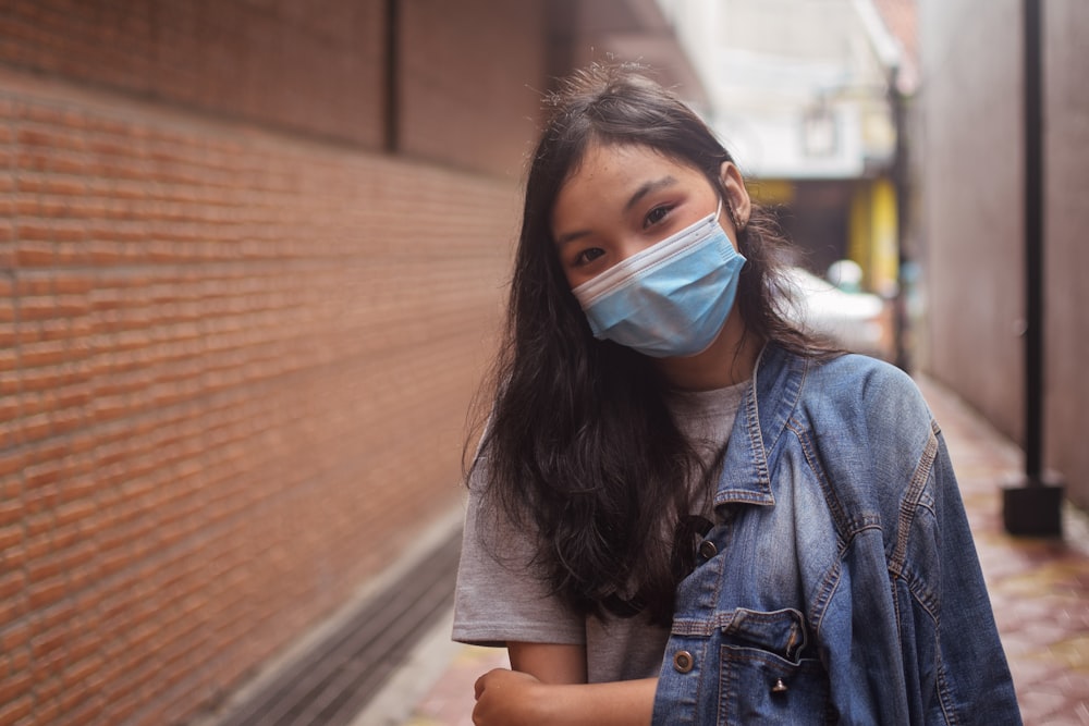 Mujer en chaqueta vaquera azul abotonada con mascarilla blanca