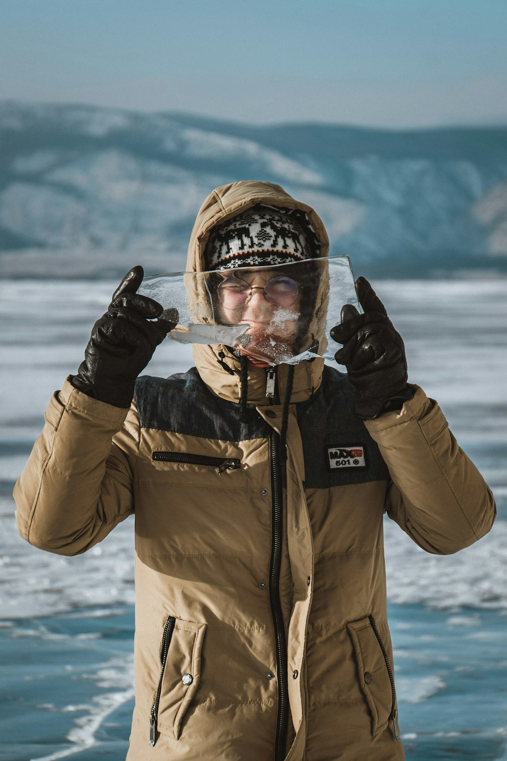 man in brown and black zip up jacket standing near body of water during daytime