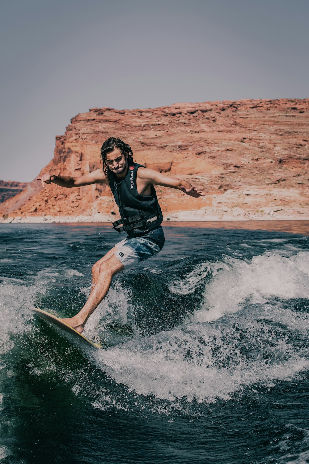 woman in black shirt and blue denim shorts surfing on sea waves during daytime