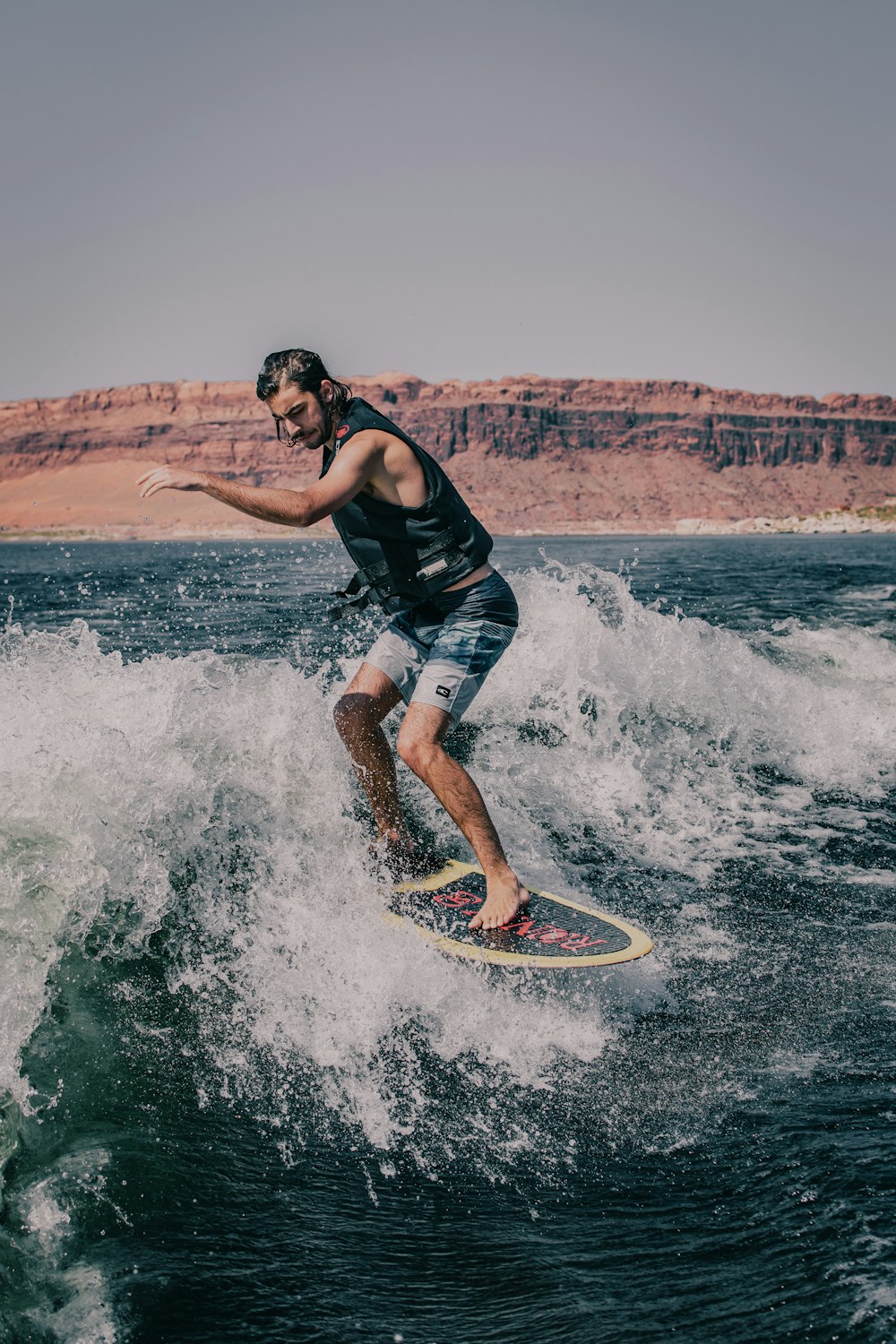 man in black tank top and blue shorts surfing on sea waves during daytime