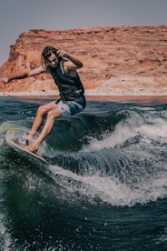 woman in black shirt and blue denim shorts surfing on water waves during daytime