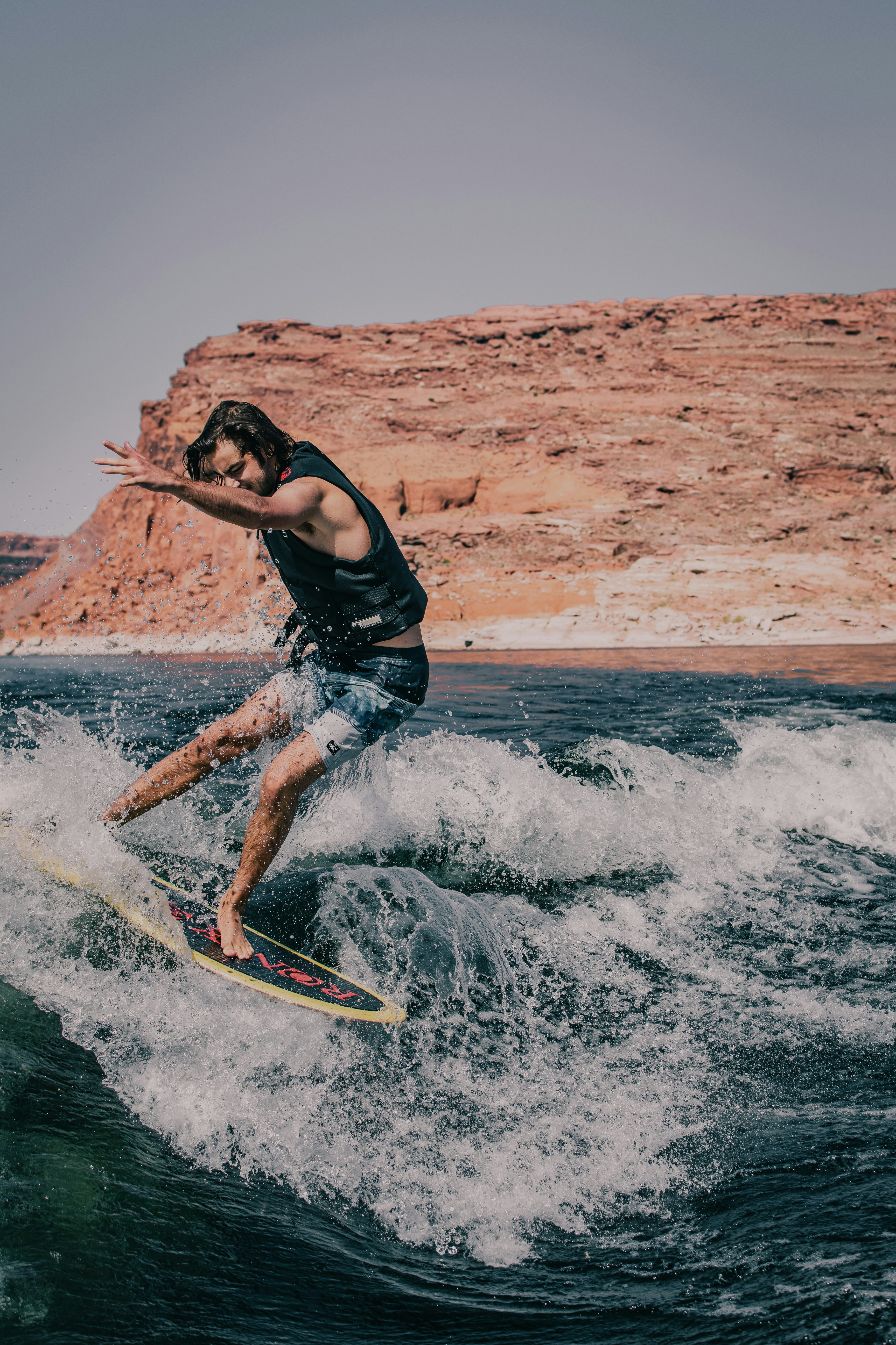 man in black tank top and blue denim shorts surfing on sea waves during daytime