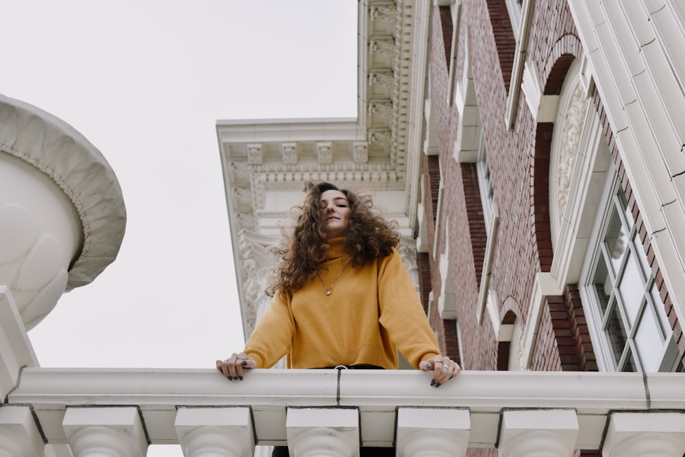 woman in yellow long sleeve shirt sitting on white concrete bench during daytime