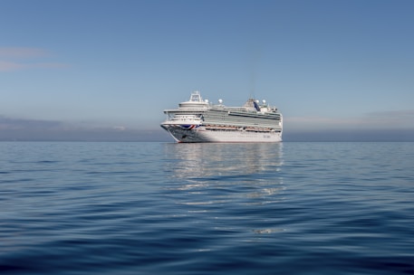 A scenic cruise ship sailing on calm blue waters under a clear sky.