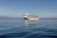 A joyful family relaxing on the deck of a modern cruise ship under a clear blue sky.