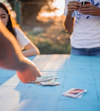 woman in white tank top and blue denim shorts standing near white smartphone on table
