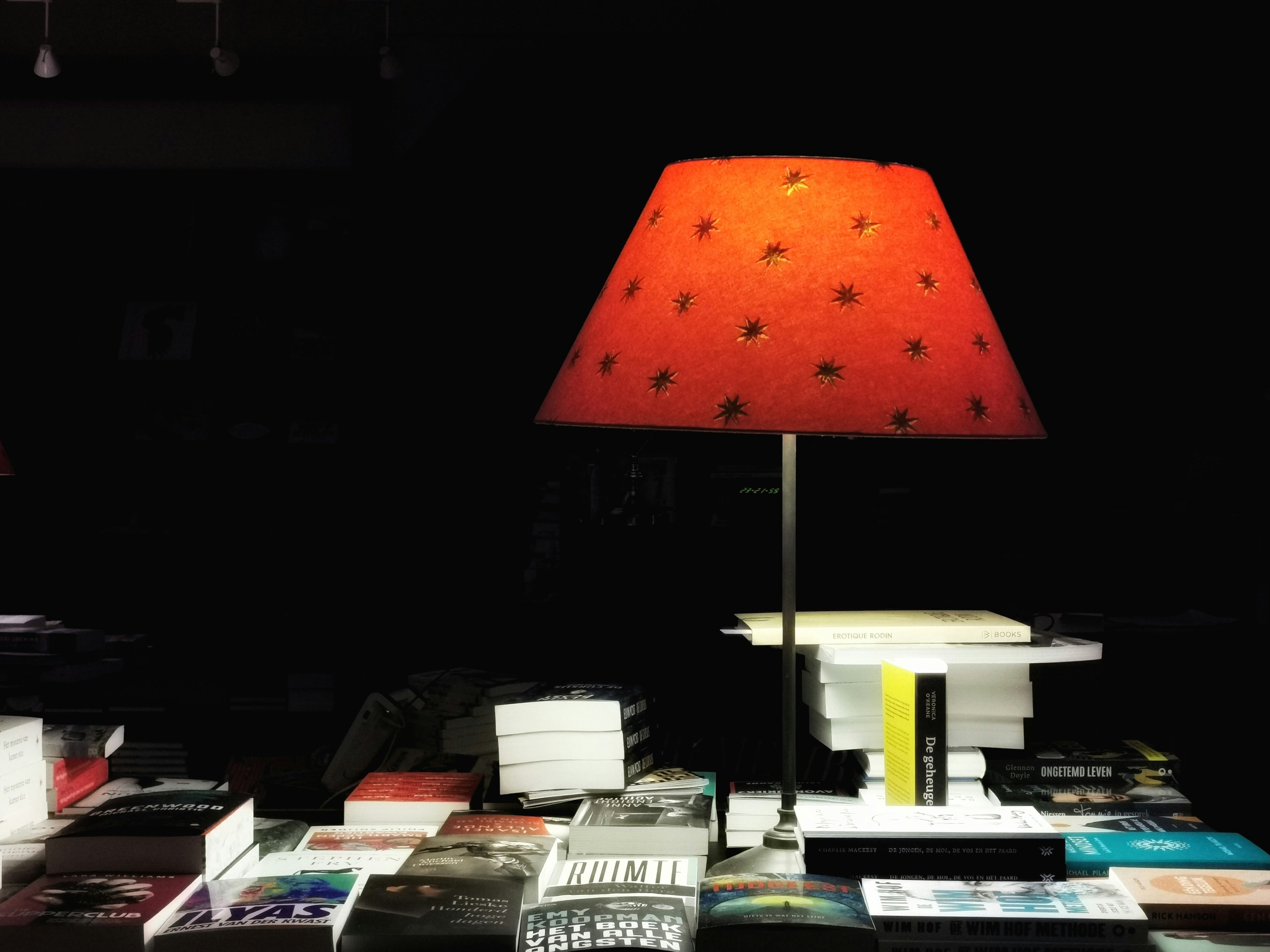 red table lamp turned on beside books