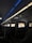 An interior view of an airplane cabin featuring several rows of seats. Each seat is equipped with a personal screen displaying a welcome message and an image of rock formations at sunset. The lighting is dim with a blue ambiance from the overhead compartments.