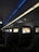 An interior view of an airplane cabin featuring several rows of seats. Each seat is equipped with a personal screen displaying a welcome message and an image of rock formations at sunset. The lighting is dim with a blue ambiance from the overhead compartments.