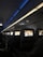 An interior view of an airplane cabin featuring several rows of seats. Each seat is equipped with a personal screen displaying a welcome message and an image of rock formations at sunset. The lighting is dim with a blue ambiance from the overhead compartments.