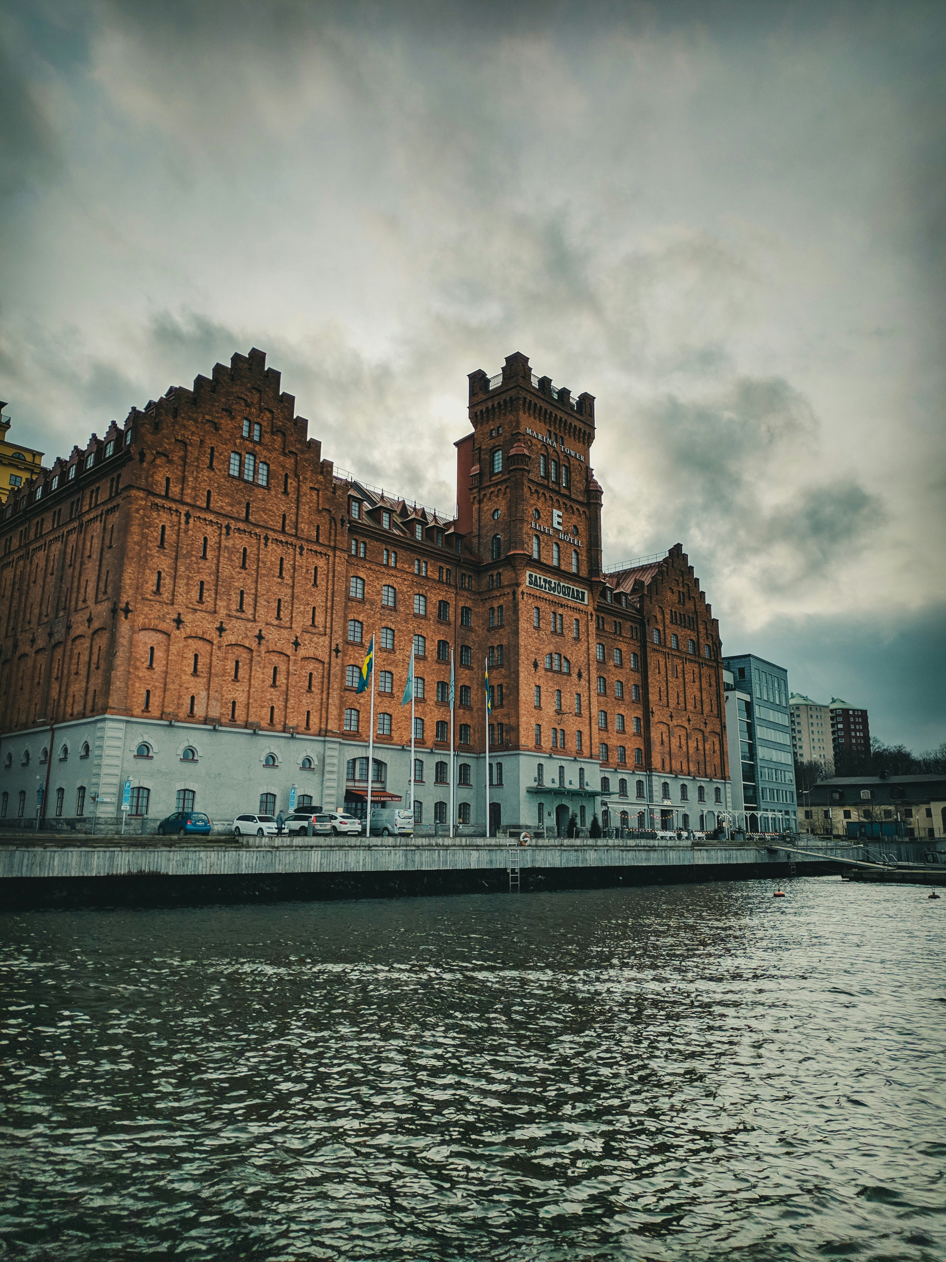 brown and white concrete building beside body of water under cloudy sky during daytime