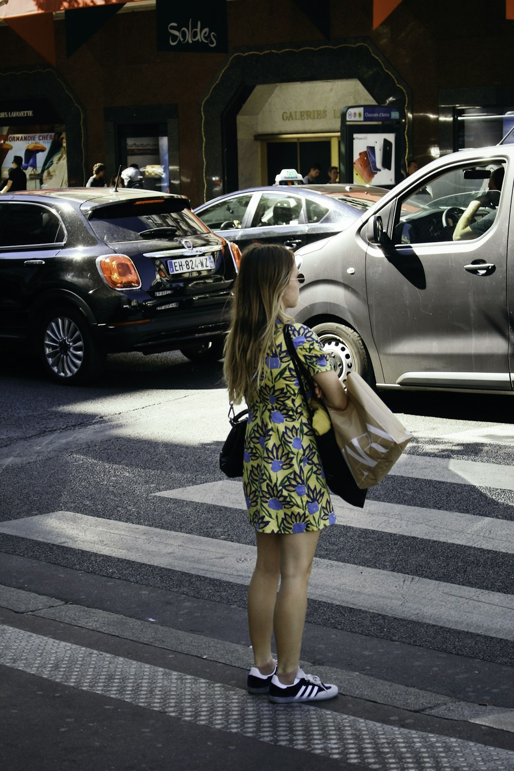 woman in blue and white floral dress standing on pedestrian lane during daytime
