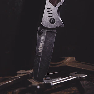 Close-up of a sleek stainless steel surgical instrument resting on a parchment-colored surface with a subtle deep crimson background.