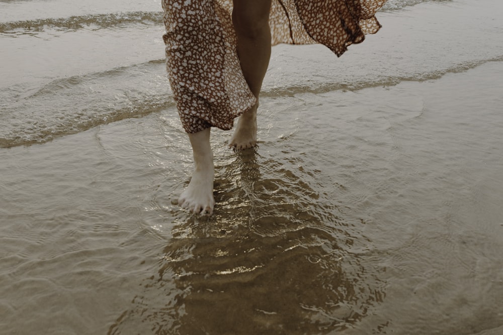 woman in red and white floral dress walking on beach during daytime
