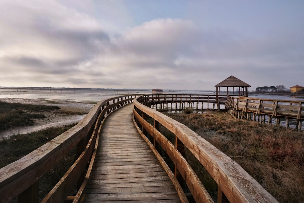 灰色の曇り空の下のビーチに架かる茶色の木製の橋
