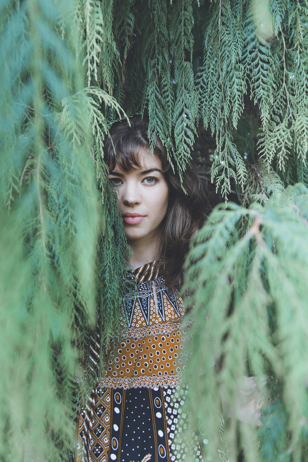 woman in brown and black dress standing beside green tree