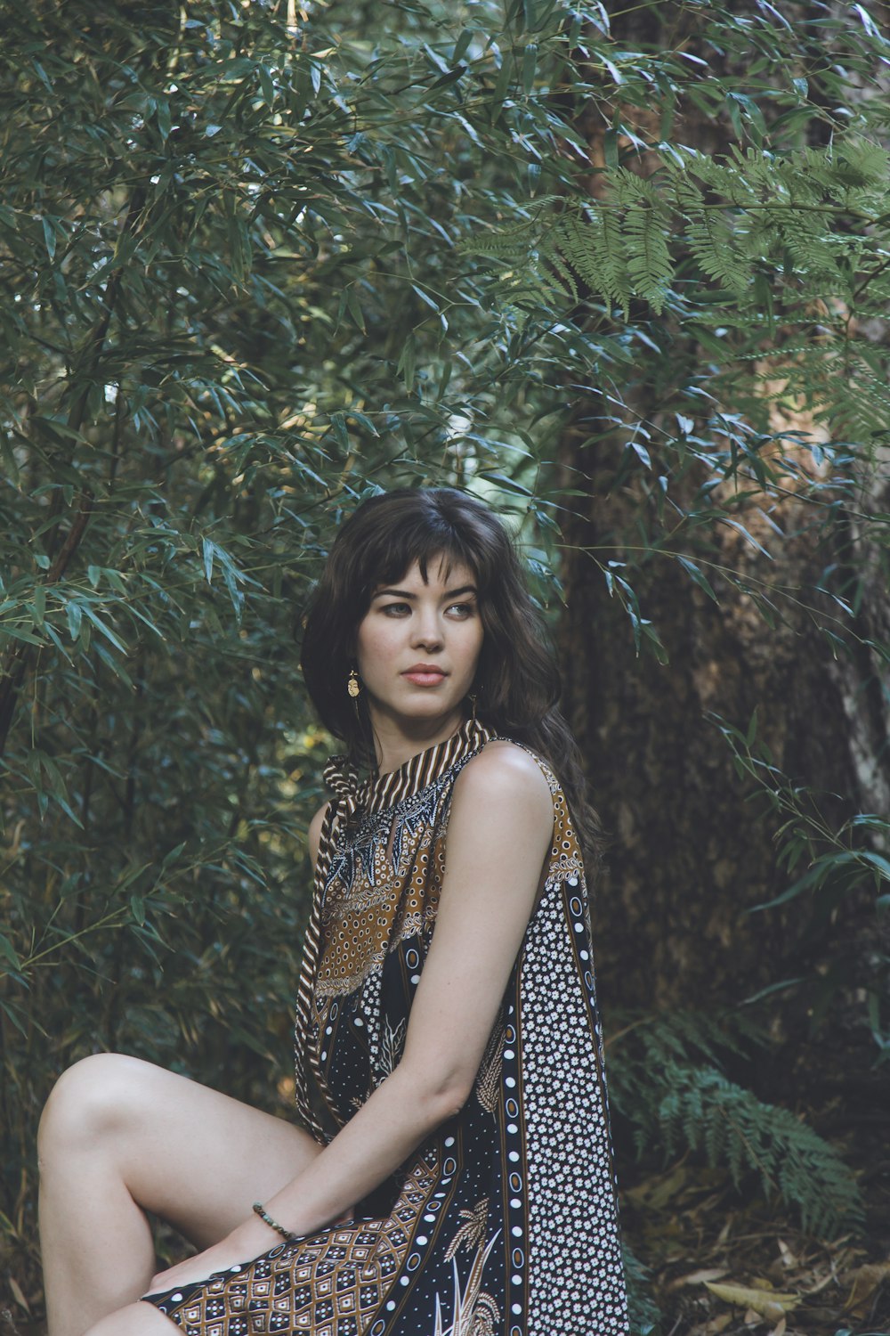 woman in black and brown leopard print sleeveless dress sitting on green grass