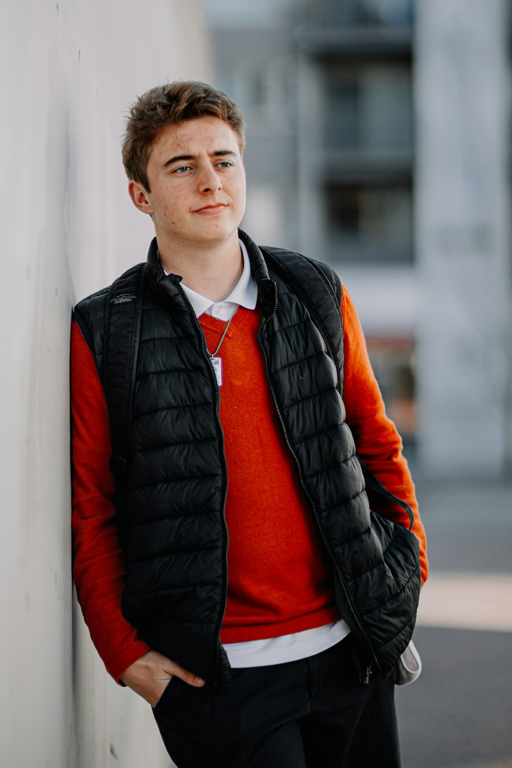 man in black leather jacket standing beside white wall