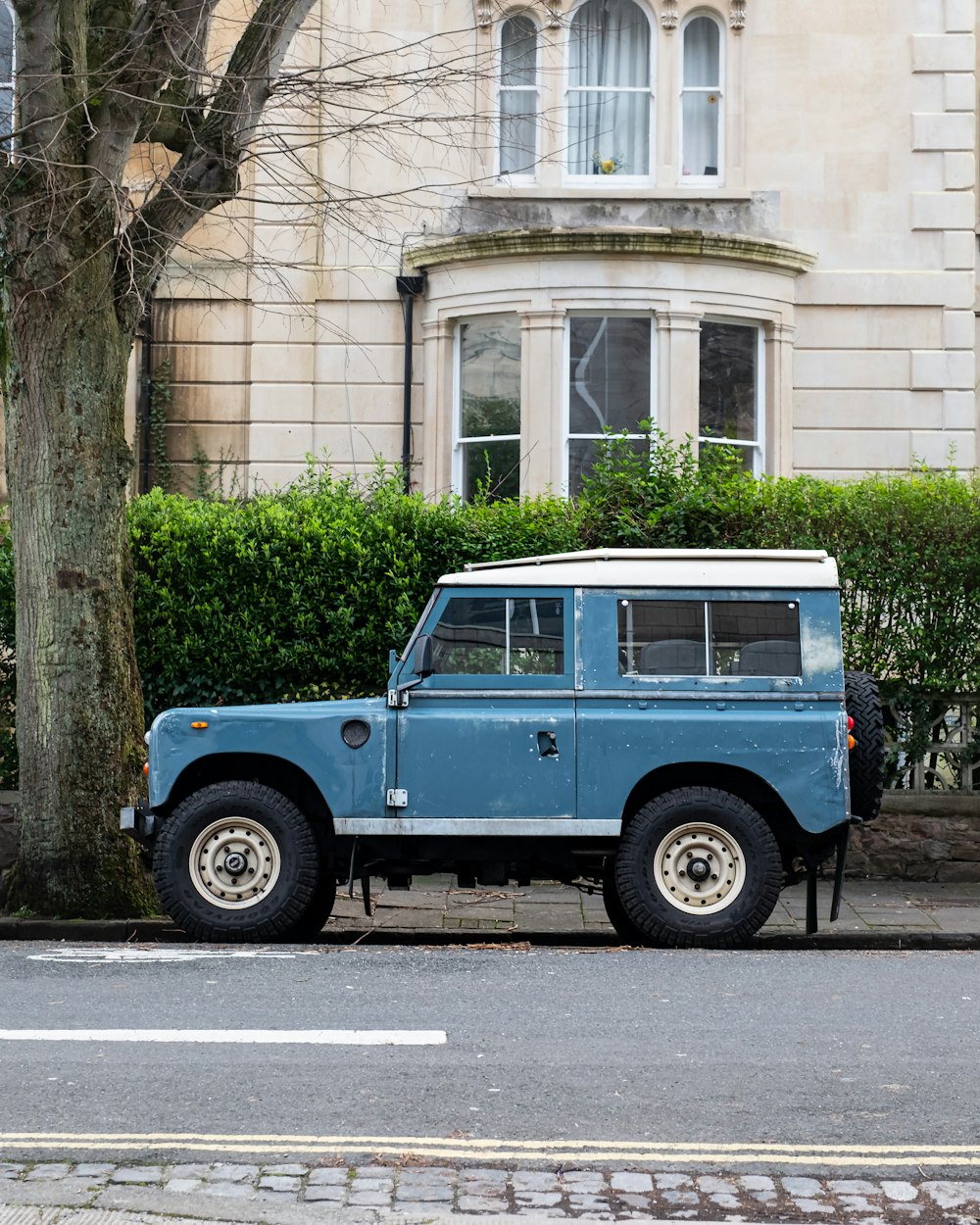 blue and white jeep wrangler parked beside brown concrete building during daytime